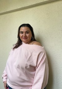 Sweatshirt oversized rosa claro com design à luz dos ombros, tecido texturizado, punhos canelados e corte descontraído. Fundo liso.