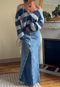 Prugasta vunena cardigan u sivoj i mornarskoj plavoj, u kombinaciji s plavom traper maxi suknjom koja ima prednji prorez i strgane rubove. Srebrna torbica kao dodatak.