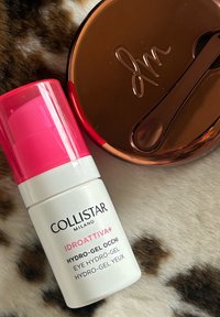 Collistar Idroattiva+ Υδρο-Τζέλ, λευκό μπουκάλι με ροζ καπάκι, τοποθετημένο δίπλα σε ένα καφέ κυκλικό δοχείο και ένα μικρό κουτάλι σε φόντο από γούνα.