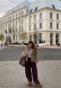 Καφέ ψεύτικη γούνα μπουφάν, λευκή κοντή μπλούζα, μπορντό ριγωτά φαρδιά παντελόνια, καφέ πλατφόρμες, κρατώντας μια μεγάλη μπορντό τσάντα; αστική τοποθεσία.