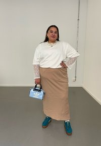 Λευκό μπλουζάκι με δαντελένια μανίκια, μπεζ φούστα, ανοιχτό μπλε τσάντα, τιρκουάζ παπούτσια με καφέ σόλες. Μαργαριταρένιο κολιέ ως αξιοσημείωτο αξεσουάρ.