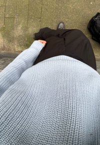 Ανοιχτό μπλε πλεκτό πουλόβερ με υφαντό σχέδιο, συνδυασμένο με μαύρο παντελόνι. Η θέα είναι από ψηλά, δείχνοντας την εμφάνιση σε ένα χαλαρό περιβάλλον.