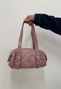 Ροζ δερμάτινη τσάντα χειρός με δύο κοντές λαβές, πλευρικές τσέπες, ασημί εξαρτήματα και υφή. Συμπαγές ορθογώνιο σχήμα.