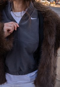 Nike sivkasti pulover od flisa s četvrtastim patentnim zatvaračem, s bijelim logotipom. Ukrašen smeđim krznenim vanjskim slojem, meke teksture.