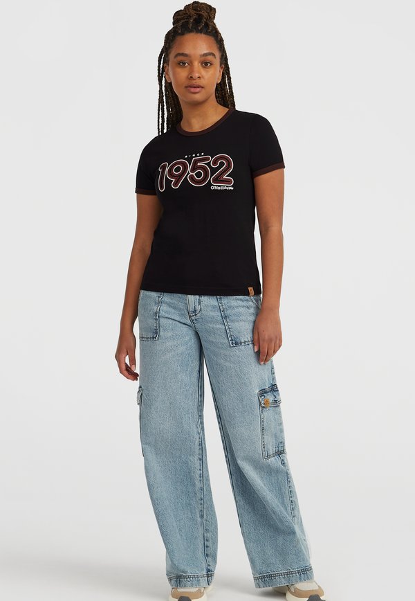 Schwarzes Baumwoll-T-Shirt mit kurzen Ärmeln, das ein farbenfrohes "1952"-Grafikdesign zeigt. Kombiniert mit hellblauen weiten Cargo-Jeans mit Taschen.