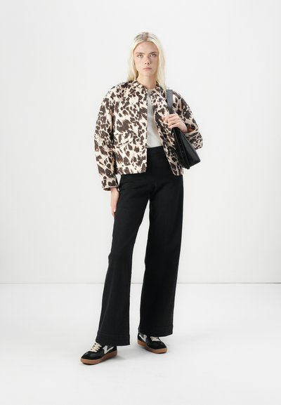 Chaqueta acolchada de leopardo, camisa blanca, pantalones negros de cintura alta, zapatillas negras con detalles blancos y un bolso negro de hombro.