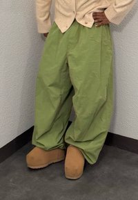 Pantalon ample vert olive en tissu léger, associé à des sabots beige à plateforme, avec une texture lisse et un bout arrondi.