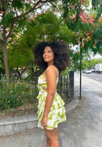 Vestido con volantes en un patrón de cuadros blanco y verde, con tirantes finos y un diseño en capas. Usado con un fondo al aire libre.