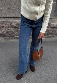 Lys beige kabelstrikket cardigan, høyt liv blå vide jeans, brune hæl ankle boots og en brun lær skulderveske.