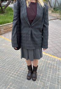 Grå ternet oversized blazer, mørk maroon skjorte, grå plisseret nederdel og brune læder ankelstøvler, med en sort quiltet taske.
