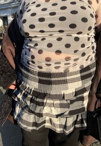 Jupe à couches noire et blanche avec des détails à volants, associée à un haut transparent noir et blanc à pois, mettant en valeur diverses textures et motifs.