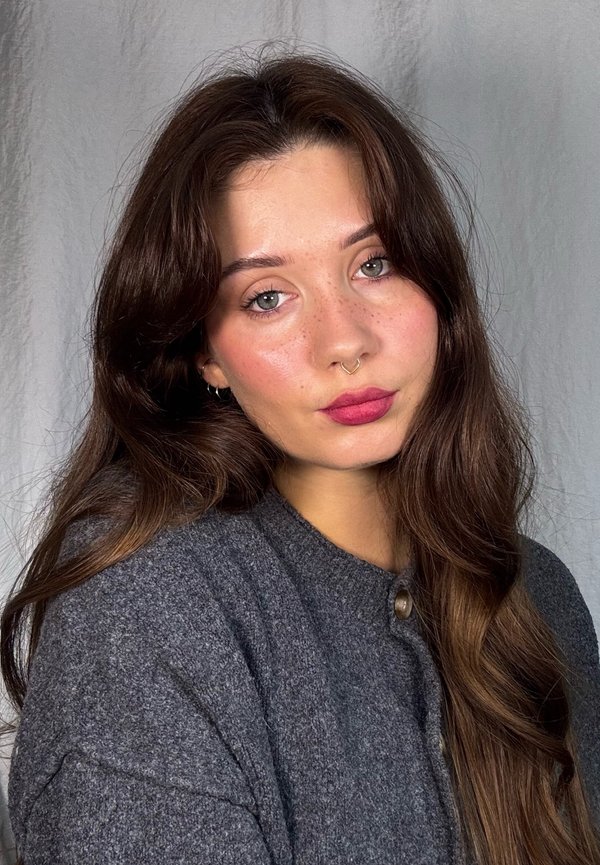 Gray wool cardigan with round neckline and a button detail, worn by a person with long, wavy brown hair and natural makeup.