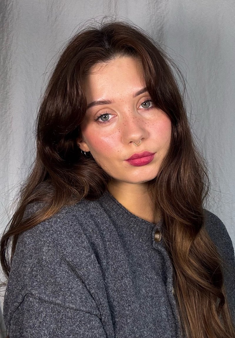 Gray wool cardigan with round neckline and a button detail, worn by a person with long, wavy brown hair and natural makeup.