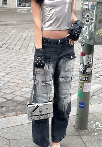 Μαύρο και γκρι cargo παντελόνι με πολλές τσέπες, συνδυασμένο με μεταλλικό ασημένιο crop top και γάντια χωρίς δάχτυλα μαύρου χρώματος με καρφιά. Μια ασημένια τσάντα χιαστί ολοκληρώνει την εμφάνιση.