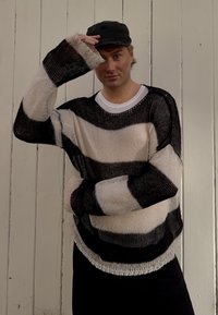 Zwart en crèmekleurig gestreepte oversized gebreide trui met een losse pasvorm en een wijde halslijn, voorzien van rafelende boorden en onderrand.