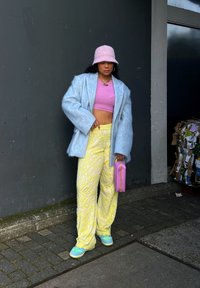 Svetlomodrý, nadýchaný oversized kabát, ružový skrátený top, žlté široké nohavice s vzorom, modrožlté tenisky a malá ružová kabelka.