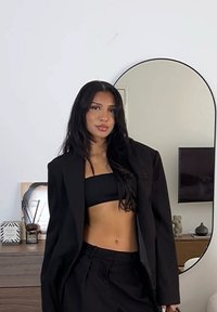 Svart oversized blazer over en svart crop top og skreddersydde bukser. Glatt stoff med en avslappet passform som viser en minimalistisk estetikk.