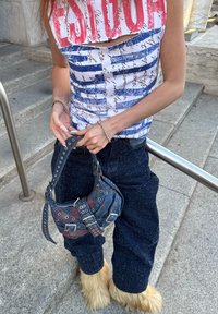 Sinivalkokuvioinen hihaton paita yhdistettynä ylivertaisiin tummiin farkkuihin ja moniväriseen, niitillä koristeltuun käsilaukkuun. Erityiset karvaiset jalkineet.