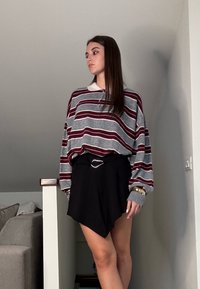 Sivorj in maroon prugast oversized pulover z belim ovratnikom, v kombinaciji s črno asimetrično krilo in pasom s srebrnim poudarkom.