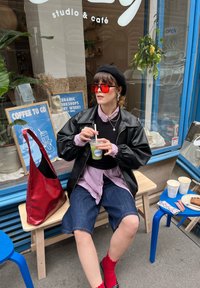 Μαύρο δερμάτινο μπουφάν, ροζ πουκάμισο, τζιν σορτσάκια, κόκκινες κάλτσες, κόκκινα γυαλιά ηλίου και μια κόκκινη τσάντα. Διαφανές ποτήρι με ένα ρόφημα. Μπλε τραπέζι με ροφήματα και ζαχαροπλαστική.