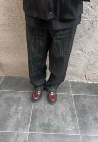 Breite, dunkle Jeans mit dezenten vertikalen Streifen, kombiniert mit glänzenden kastanienbraunen Loafers mit Stichdetail und runder Zehenpartie.