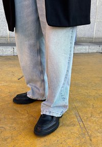 Ανοιχτό μπλε, φαρδιά τζιν παντελόνια σε συνδυασμό με μαύρες, χοντρές loafers με λείο δέρμα και στρογγυλή μύτη.