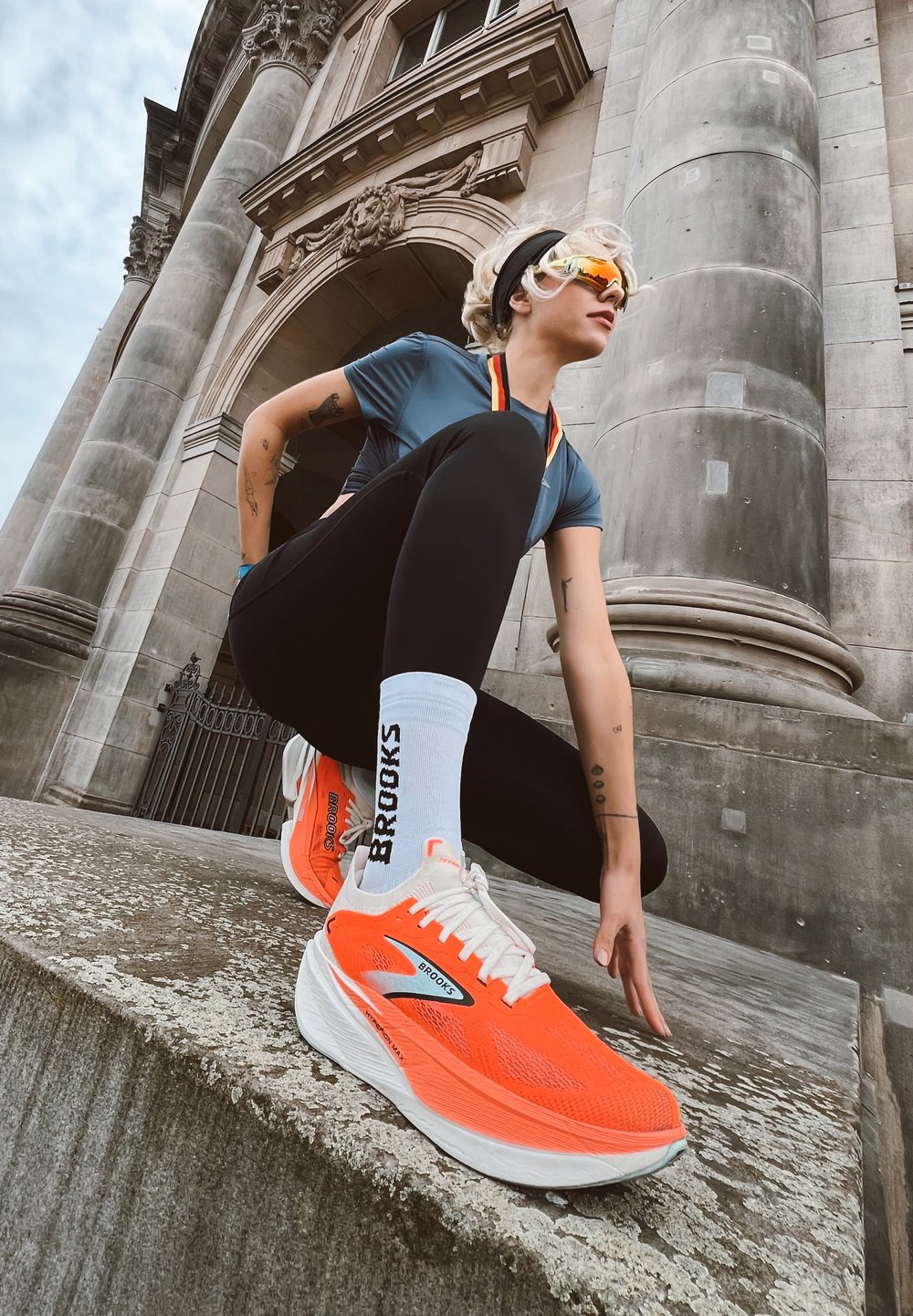 Zapatillas de running de un vibrante color naranja con suelas blancas y la marca "Brooks". La parte superior tiene un acabado texturizado; los cordones son de color naranja neón.