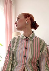 Triibuline särk, millel on rohelised, roosad ja lavendlivärvi vertikaalsed triibud, nööpidega esiküljel ja kraega. Hõbedased kõrvarõngad ja kuklisoeng.