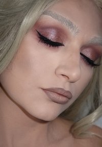 Nahaufnahme eines Gesichts mit glatter, heller Haut. Betont mit dicker Lidschatten in Rosa- und Brauntönen, markantem Eyeliner und mattem nude Lippenstift.