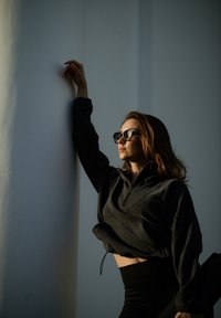 Black quarter-zip pullover with a textured finish, paired with high-waisted black leggings. Soft sunlight accentuates the outfit.
