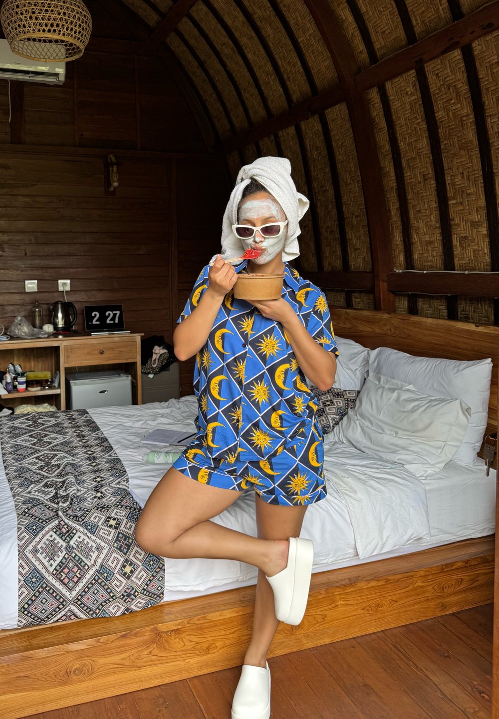 Blauwe pyjama set met een patroon van gele zonnen en halve manen, gecombineerd met witte instap schoenen. Persoon houdt een kom en een lepel vast.