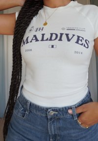 Hvit bomulls T-skjorte med "MALDIVES" trykt i marineblått, med årene "2008" og "2014" under. Kombinert med høyhansede denimshorts.