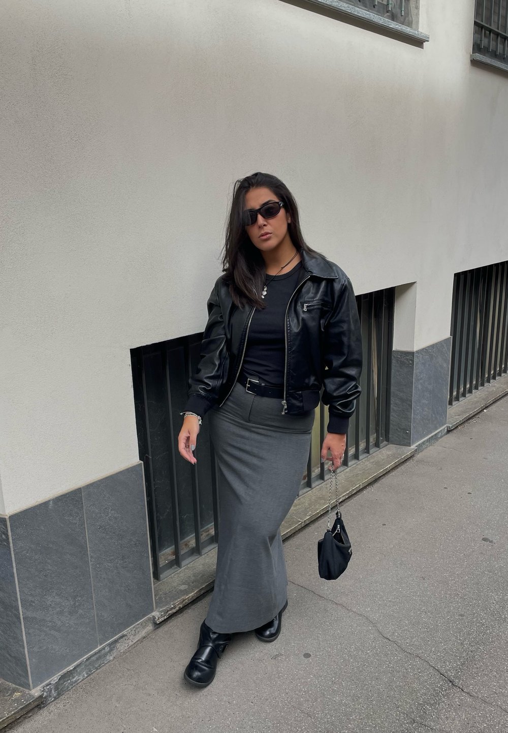 Μαύρο δερμάτινο κοντό σακάκι, εφαρμοστό μαύρο τοπ, γκρίζα μολυβένια φούστα και μαύρες μπότες. Αξεσουάρ: μικρή μαύρη τσάντα με αλυσίδα.