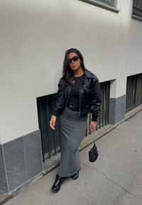 Μαύρο δερμάτινο κοντό σακάκι, εφαρμοστό μαύρο τοπ, γκρίζα μολυβένια φούστα και μαύρες μπότες. Αξεσουάρ: μικρή μαύρη τσάντα με αλυσίδα.