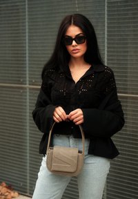 Μαύρο πουκάμισο με κουμπιά και δαντελένιες λεπτομέρειες, μαύρη εξωτερική ζακέτα, ανοιχτό μπλε τζιν, και γκρι τσάντα με υφή με κυρτή καπάκι.