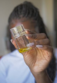 Botella de vidrio transparente de aceite de unión Olaplex No. 7, que contiene aceite amarillo, con texto negro y una tapa de rosca transparente.