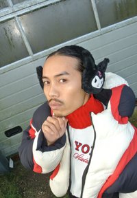 Jachetă pufosă cu secțiuni albe, roșii și negre; pulover roșu; căciuliță pufoasă neagră cu fața unui personaj; persoană pozând gânditor.