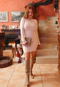 Κομμάτι που αγκαλιάζει τη σιλουέτα, πλεκτό φόρεμα μακρυμάνικο σε απαλό ροζ με διαμαντένια μοτίβα; συνδυασμένο με μπεζ μπότες γόνατος με ραφές και μπεζ τσάντα χειρός.