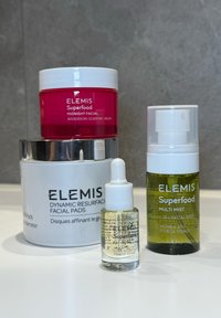 Cztery produkty do pielęgnacji skóry ELEMIS: różowy słoik, srebrny słoik, szklana butelka z pipetą oraz zielony spray w mgiełce, wszystkie z wyraźnymi, oznakowanymi opakowaniami.