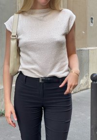 Ανοιχτό μπεζ ριγωτό πλεκτό μπλουζάκι με τσέπες, συνδυασμένο με μαύρο εφαρμοστό παντελόνι και κρέμα τσάντα χειρός. Μινιμαλιστικός σχεδιασμός, υφή υφάσματος.