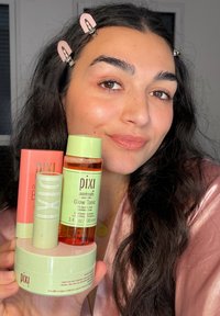 Drei Hautpflegeprodukte von Pixi sind ausgestellt: ein grüner Toner, eine pfirsichfarbene Creme und ein pastellfarbener Behälter, alle auf einer runden Basis mit auffälligen Etiketten.