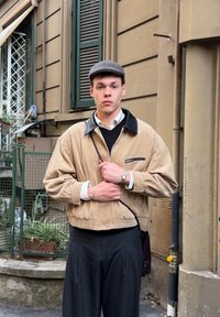 Bež žametna jakna s črnim ovratnikom, dolgimi rokavi in sprednjim žepom z zadrgo. Črne nabrane hlače in srečna zapestna ura. Nosen je bil tudi kapuca z ravnim vizirjem.