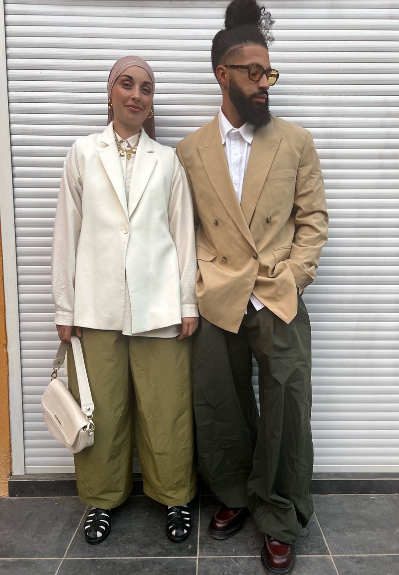Crèmekleurig colbert, olijfgroene wijde broek, gebloesd blouse, beige double-breasted jasje, bruine loafers, witte handtas, gestructureerde sjaals.