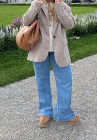 Harmaa ruudullinen bleiseri kermanvärisen neuleen päällä, yhdistetty vaaleansinisiin levenevin lahkeisiin farkkuihin ja konjakinvärisiin mokkanahkaisiiin nilkkureihin. Iso konjakinvärinen käsilaukku täydentää asun.