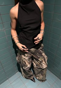 Fekete pánt nélküli felső, terepmintás cargo nadrággal, melyen foltzsebek találhatók, a megjelenést hegyes orrú fekete bokacsizma és rétegzett ezüst gyűrűk teszik teljessé.