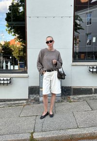 Γκρι υπερμεγέθης πουλόβερ, λευκό σορτς, μαύρες μπαλαρίνες με πουά και μία τσάντα με σχέδιο. Λείο ύφασμα, χαλαρή εφαρμογή και μονοχρωματική χρωματική παλέτα.