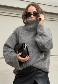 Szürke, nagy méretű garbós pulóver puha textúrával; fekete clutch-sal párosítva. Fekete nadrág enyhe fényű. Kiegészítők között gyűrűk találhatók.