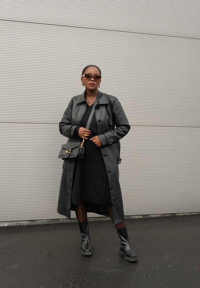 Μαύρο δερμάτινο παλτό, ριγέ μαύρο φόρεμα, μαύρη τσάντα με χρυσές λεπτομέρειες και μαύρες μπότες μέχρι το γόνατο. Απλά αξεσουάρ, απλές υφές.