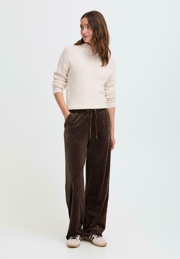 Hnedé kordové nohavice so širokým strihom, elastickým pásom a šnúrkou. V kombinácii s krémovým svetrom a teniskami.