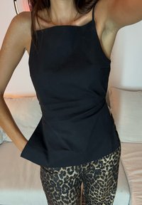 Black sleeveless top featuring a square neckline and peplum design, matched with brown leopard-print trousers. The fabric looks smooth and tailored.